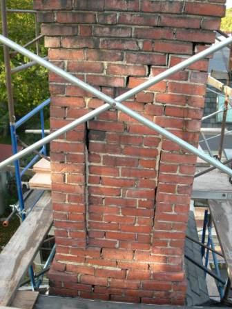 Before repairs cracks in brick chimney with scaffolding in background