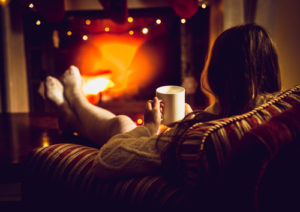 Cozy picture of someone sitting in front of the fire with a hot beverage