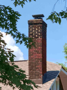 masonry chimney with cap behind tree branches - Boston MA - Billy Sweet Chimney Sweep